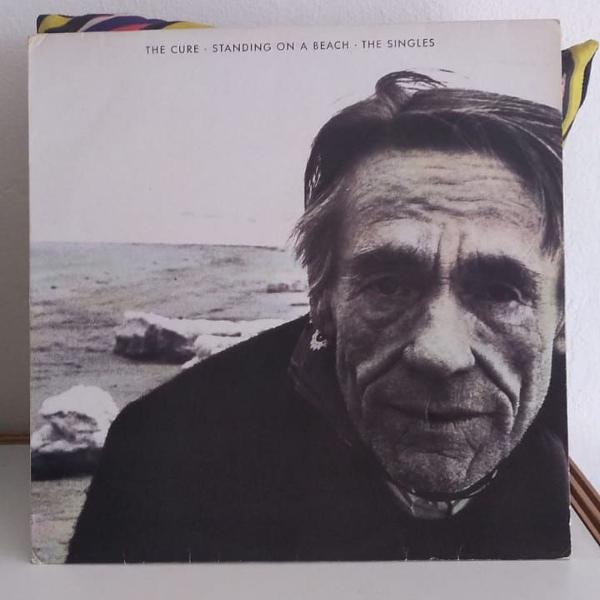 lp vinil disco standing on a beach - the singles - the cure
